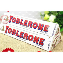 Two Toblerone Swiss white chocolate bars with honey and almond nougat on a table.