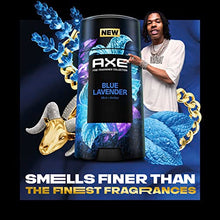 Adele A. wearing a white shirt and gold jewelry stands next to an Axe deodorant stick in a stylized promotional graphic with blue mint leaves, a gold ram head, and bold text reading 'NEW' and 'SMELLS FINER THAN THE FINEST FRAGRANCES'.