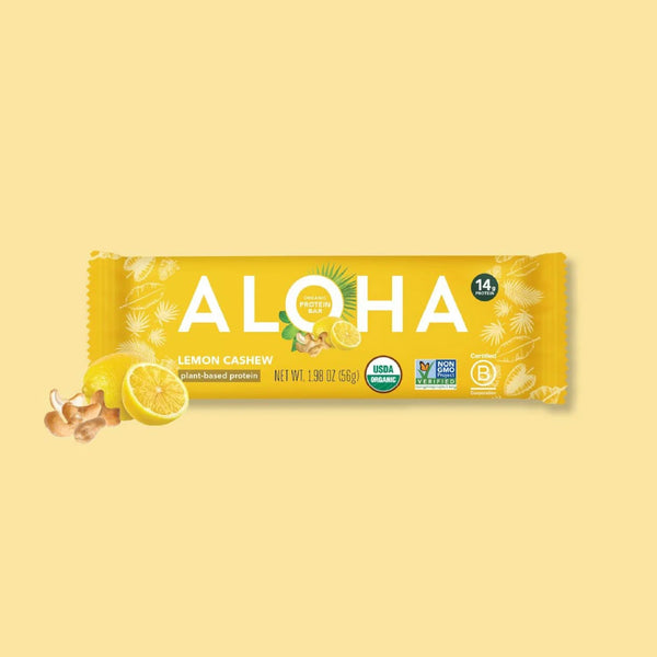 ALOHA Organic Lemon Cashew plant-based protein bar with fresh lemon slices on a yellow background
