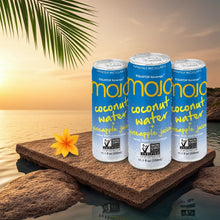 Mojo coconut water and pineapple juice cans on rocks by tropical sunset, palm leaf and flower