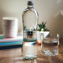 Aqua Carpatica natural sparkling mineral water bottle with glass on wood table, ideal for hydration