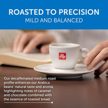 Hand holding an illy espresso cup with coffee, open book in background, roasted to precision text.