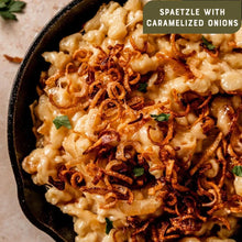 Spaetzle with caramelized onions in cast iron skillet, creamy pasta topped with crispy fried onions and herbs
