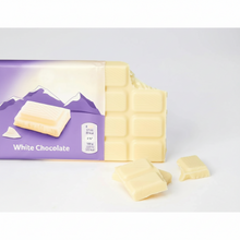 Creamy white chocolate bar with purple mountain packaging, broken pieces beside, premium snack