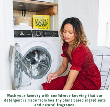 Woman in red dress loading front-load washing machine with plant-based lemongrass laundry soap.