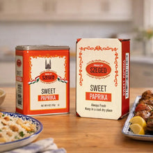 Sweet Paprika from Szeged in tin and box, displayed with rice and grilled meat on kitchen table