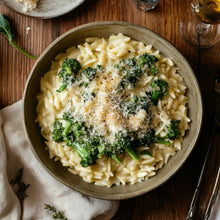 Creamy orzo pasta with broccoli, parmesan cheese, and black pepper in rustic bowl