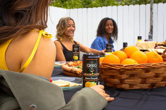 CRODO Aranciata Italian orangeade can at outdoor picnic with fresh oranges and friends