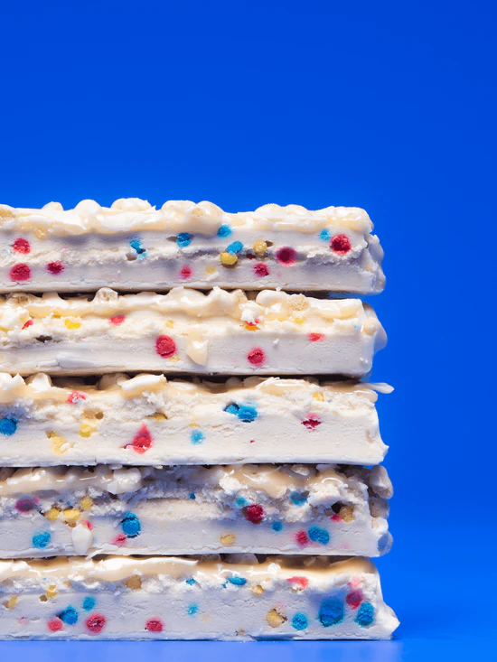 Barebells Birthday Cake bar cross section showing white chocolate coating and colorful sprinkles