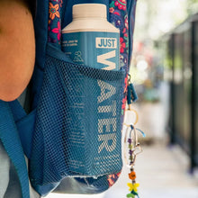 Just Water carton in mesh pocket of blue floral backpack, outdoor setting, hydration