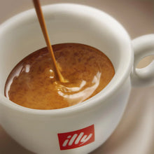 Fresh espresso being poured into a white ceramic cup with rich crema