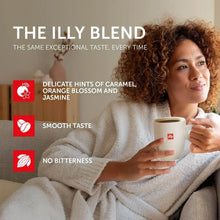 Woman in a robe enjoying illy coffee, cup in hand, with coffee taste notes highlighted on screen.