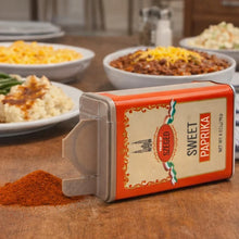 Sweet Paprika spice tin with Hungarian Szeged label, sprinkled on wooden table near bowls of chili and mashed potatoes
