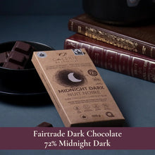Fairtrade 72% Midnight Dark Chocolate bar with Belgian cocoa, vegan, keto, no gluten or soy, beside broken pieces and books