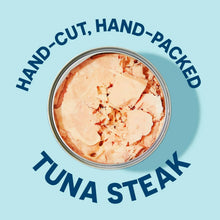 Open can of hand-cut, hand-packed tuna steak on light blue background