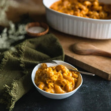 Creamy baked macaroni and cheese in a white bowl with spoon on rustic table