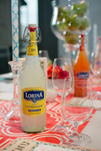 Lorina Sparkling Lemonade Prestige bottle on festive table with wine glasses, imported French pop beverage