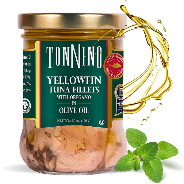 A jar of Tonnino Yellowfin tuna fillets in olive oil, featuring a gold lid, a dark green label with white text, and a splash of golden oil on a white background with fresh oregano leaves.