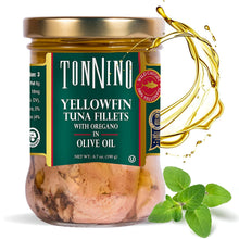 A jar of Tonnino Yellowfin tuna fillets in olive oil, featuring a gold lid, a dark green label with white text, and a splash of golden oil on a white background with fresh oregano leaves.