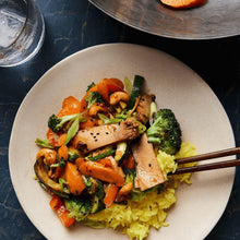 Plate of stir-fried vegetables and tuna fish over rice on a dark surface