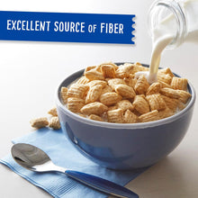 A blue bowl of fiber-rich cereal with milk being poured in, next to a spoon on a blue napkin.